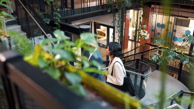 People, walk and talk in office with sustainable business, project planning and arrival at workplace. Above, coworkers and chat on stairs for eco friendly goals, environmentalist advice and meeting.