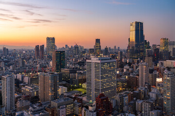 Fototapeta premium Modern Tokyo cityscape at dusk during the magic hour, featuring the illuminated Azabudai Hills skyscraper and surrounding city lights.