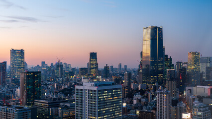 Fototapeta premium Modern Tokyo cityscape at dusk during the magic hour, featuring the illuminated Azabudai Hills skyscraper and surrounding city lights.
