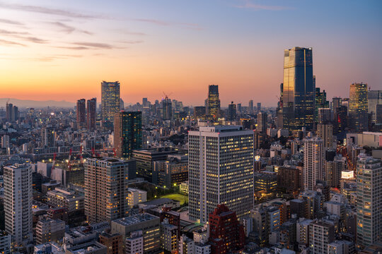 Modern Tokyo cityscape at dusk during the magic hour, featuring the illuminated Azabudai Hills skyscraper and surrounding city lights.