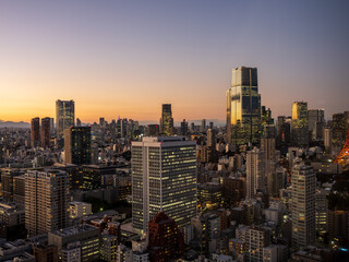 Fototapeta premium Modern Tokyo cityscape at dusk during the magic hour, featuring the illuminated Azabudai Hills skyscraper and surrounding city lights.