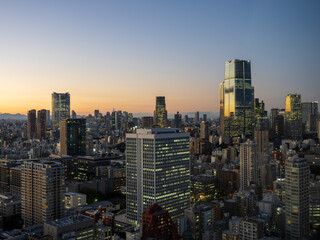 Fototapeta premium Modern Tokyo cityscape at dusk during the magic hour, featuring the illuminated Azabudai Hills skyscraper and surrounding city lights.