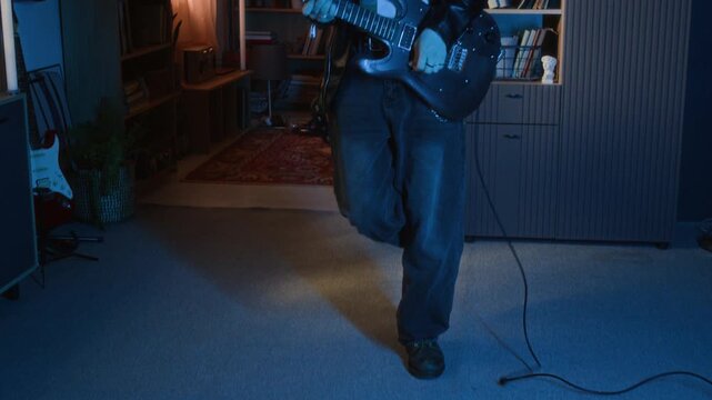 Young musician playing electric guitar and jumping in bedroom. Footage for youth culture advertisements, music education promos, or lifestyle branding targeting gen Z