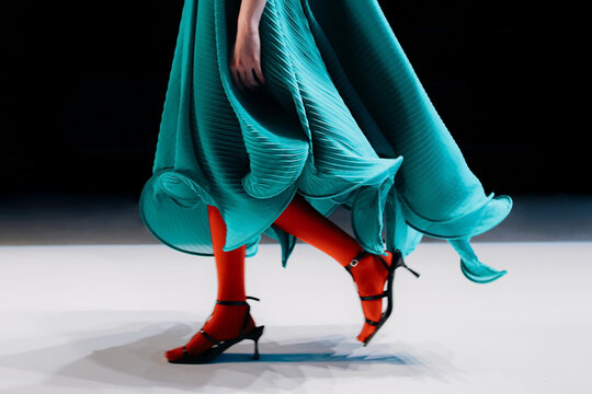 Ruffled green dress on a female figure and bright red tights, fancy woman's outfit, Fashion model walking the catwalk