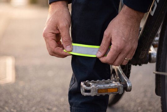 Cyclist attaching reflective safety band to pant leg