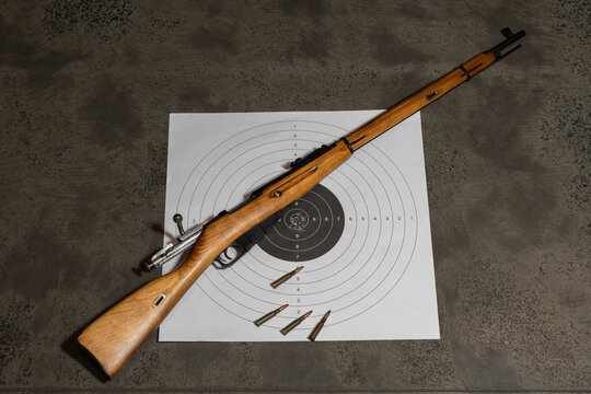 BALTIC STATES - JULY 2, 2026: Classic Mosin Nagant bolt action rifle with open straight bolt handle lying on paper target with live ammunition cartridges