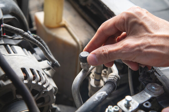 Man checking air conditioner valve of a car.