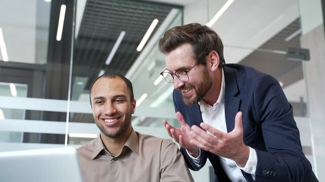 Mature manager praises young employee for excellent job at laptop in business office. Executive motivates worker for job well done. Positive communication, friendly conversation, teamwork. Close up