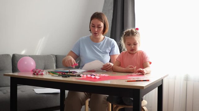 Young woman and small child working on handmade cards using paints and paper. Early education, imagination, and skill development concept. Mid shot