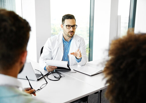 Young doctor and young couple talking in office in the clinic or hospital. Marriage and relationship problems or fertility or pregnancy concept