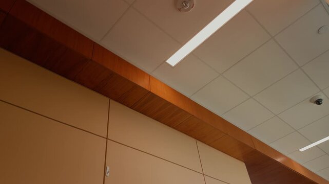 Slow upward pan across a modern commercial hallway ceiling with architectural lighting.