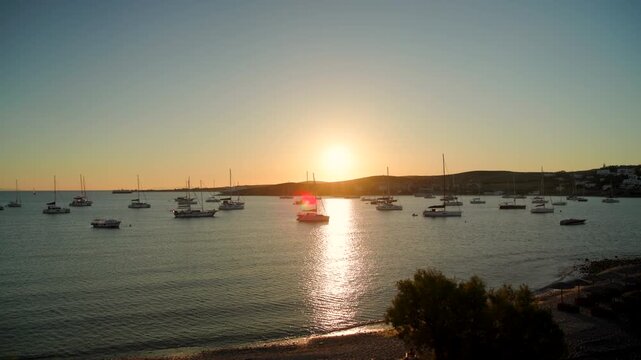 Relaxing seaside sunset with a quiet beach, gentle waves, and sailing boats on the horizon