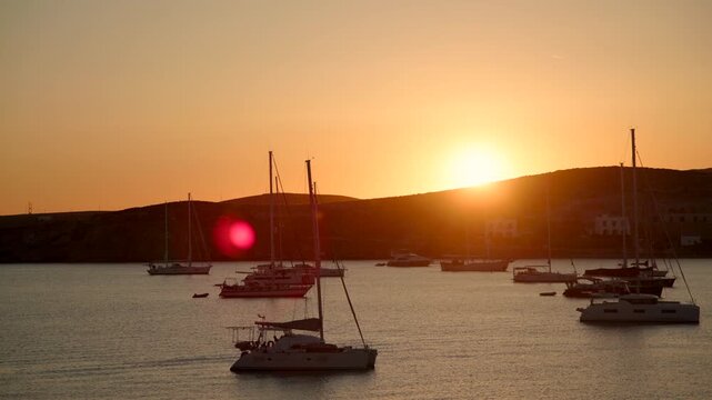 Sailboats resting on quiet waters during a vibrant sunset, creating a relaxing summer travel scene