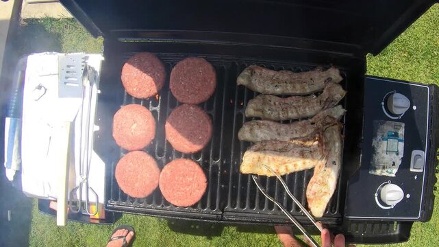 Beef burger patties cooking on gas grill outdoors with smoke