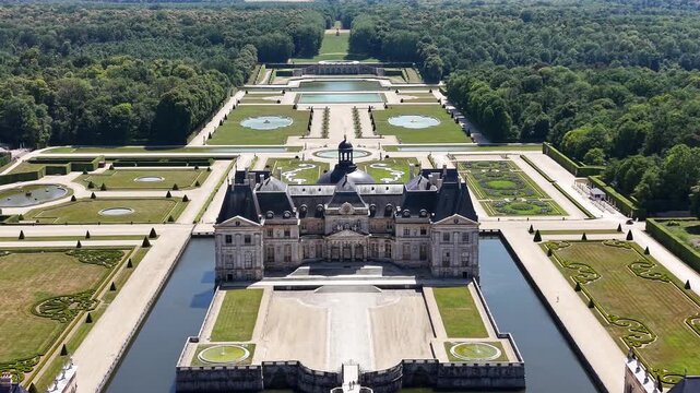 Cinematic drone aerial view centered on Ch&acirc;teau de Vaux-le-Vicomte, highlighting the symmetrical Baroque architecture, reflecting pools, formal French gardens, and grand landscaped park in Maincy