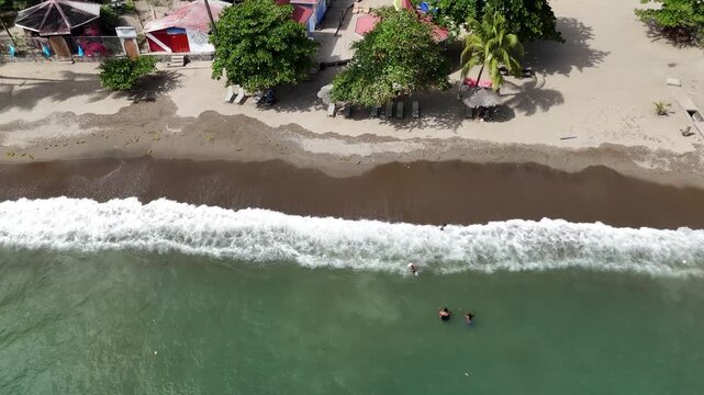 Top-down drone view of a sandy tropical beach with a small wooden boat anchored near the green coastline of Saint Lucia