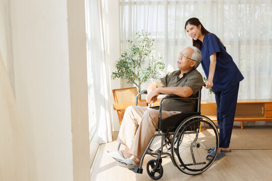 Female caregiver assists an elderly man in a wheelchair during a nursing at home visit, home care, senior care, wheelchair assistance, mobility support, and compassionate home healthcare.