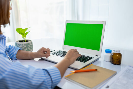 Female doctor typing laptop with green screen modern workspace wellness. Online healthcare