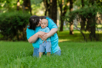 Fototapeta premium An overweight woman walks with her young son in the park in the summer. mother and son on a walk