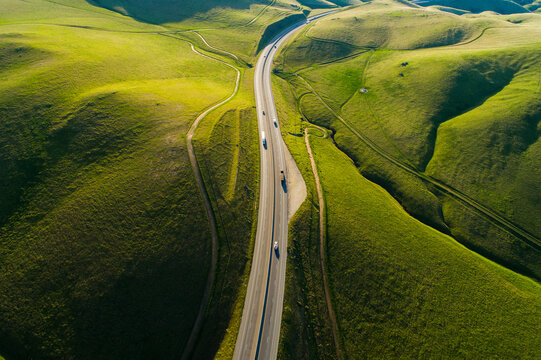 Aerial view of a highway winding through lush green rolling hills in Kern County, California, United States.