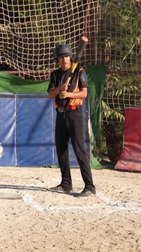 Teen boy in uniform swinging a baseball bat during training. Slow motion footage of a young athlete hitting the ball in a batting cage