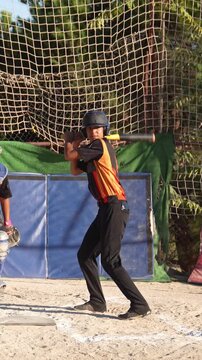 Teenage baseball player hitting the ball during a game. Slow motion footage of a young batter swinging his bat and running to first base