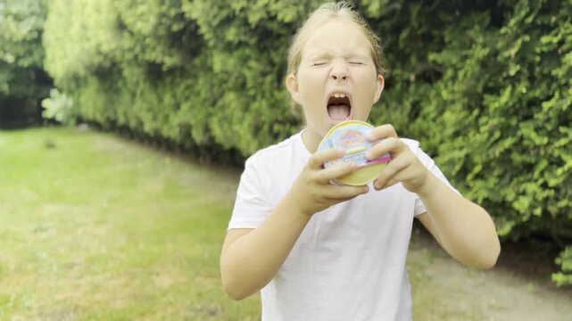 Young girl holding a snack in a green park squishy Rainbow Mystery Bun