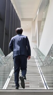  [スローモーション]オフィスでス階段を歩く中堅ビジネスマンの営業イメージ全身の顔無しの後姿の縦動画
