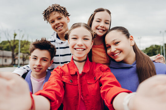 Happy group of teenage friends taking selfie together outdoors