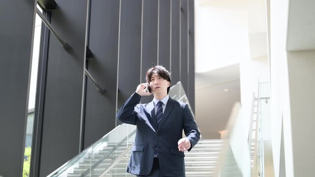  [スローモーション]オフィスでスマホで電話をしながら階段を歩くハンサムな中堅ビジネスマンの営業イメージ上半身クローズアップの動画