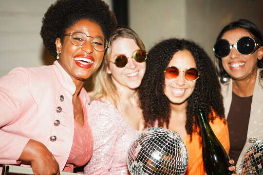 Group of multiracial girls dancing, drinking champagne and listening music outdoor - Party, summer and street nightlife concept - Main focus on african girl face - UGC flash content