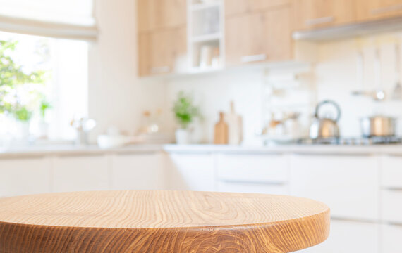 Empty round wooden table top for product design on blurred background of modern kitchen interior