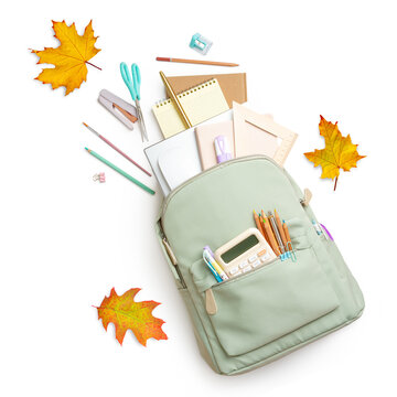 School backpack with various stationery and yellow autumn leaves on white background