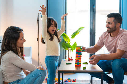 Girl celebrating victory while playing jenga with her parents