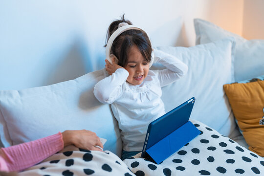 Girl using tablet and headphones sitting on the sofa