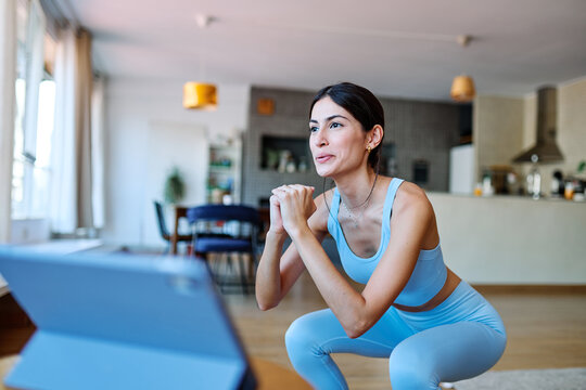 Portrait of a fit latina  girl young woman exercising practicing yoga or fitness watching online instructions tutorial on laptop at home