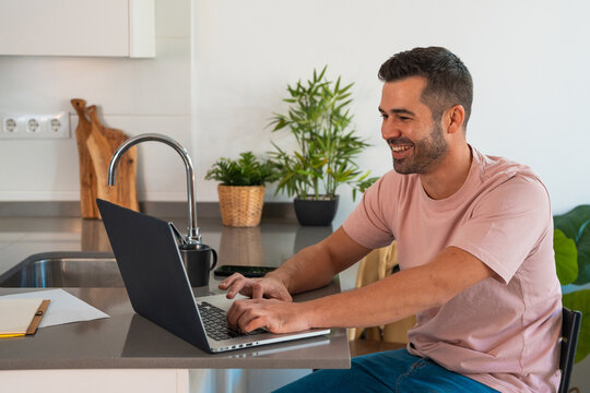 Man smiling while working from home using laptop