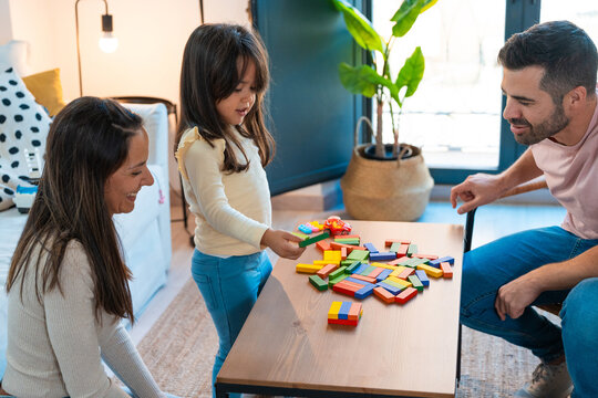 Family playing block puzzle with a little girl