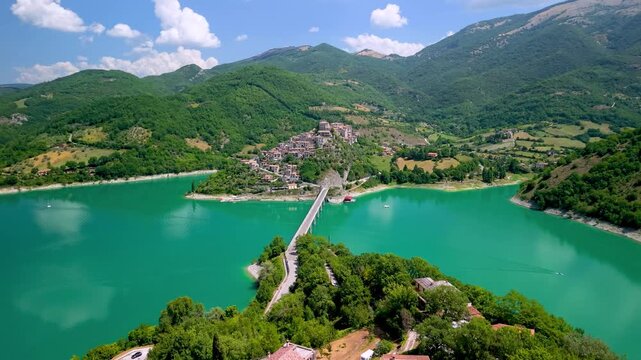 Castel di Tora Turano Lake Italy 4K Drone. Forward aerial flight over villas island to bridge on stilts medieval hilltop town. Borghi piu belli d Italia most beautiful villages cinematic footage