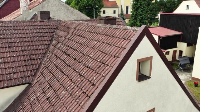Small building with dirty roof tiles, moss, lichen and weathered facade before pressure washing, exterior cleaning and roof renovation.