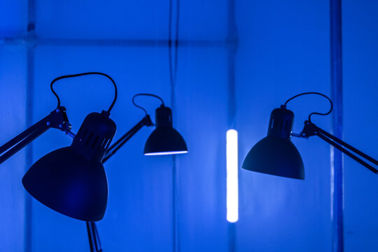 Tre lampade da ufficio e un neon su sfondo blu