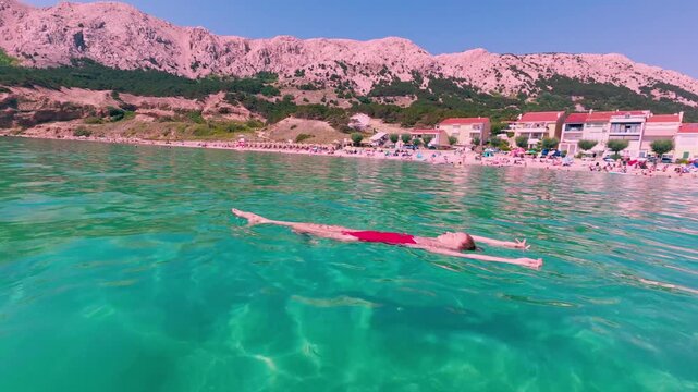 Relaxing video of a woman floating effortlessly on her back in crystal-clear turquoise Adriatic Sea