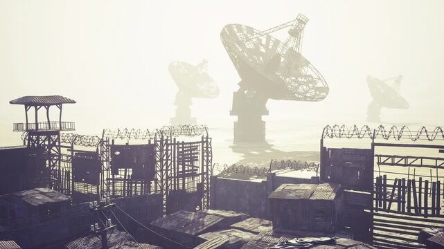 Foggy satellite compound with rusted dishes and fences, pale sunrise backlighting scene with grated platforms and scattered equipment, quiet abandonment