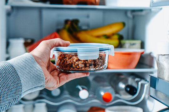 with the fridge open a man reaches for lentils