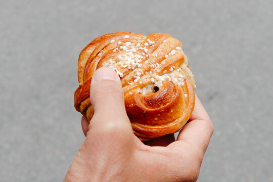 a close-up of a swedish kanelbulle held by a man