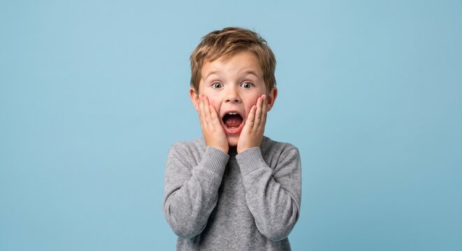 Wide-eyed wonderment on a young boy's face against a soft blue backdrop