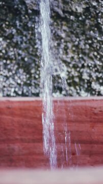 A flowing stream of clear water against a blurred background - vertical format