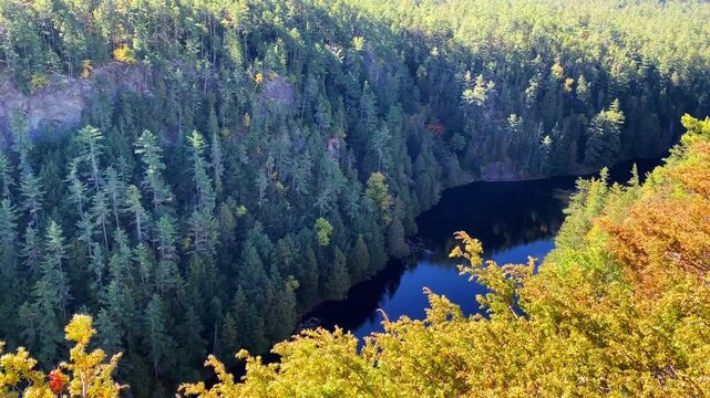 Golden autumn foliage frames a view into Barron Canyon in Algonquin Park, with rugged cliffs and evergreen forest across the canyon landscape.