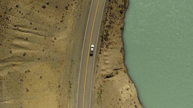 Pickup truck travels along Route 11 beside Lago Argentino in Los Glaciares National Park near El Calafate, Santa Cruz, Argentina, revealing the Patagonian steppe from directly above, top down drone tr