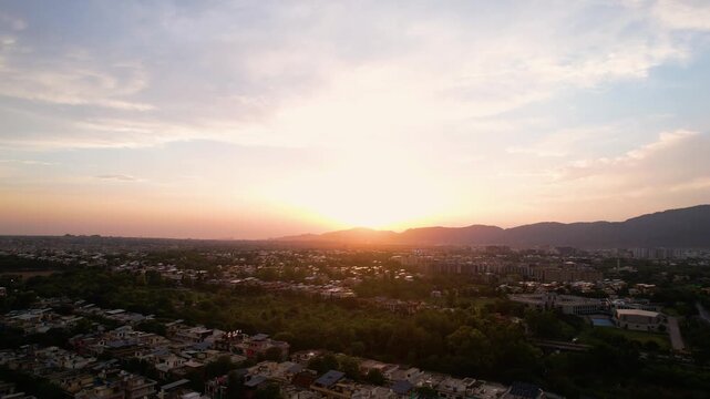 Golden sunset illuminates Islamabad cityscape with Margalla Hills silhouetted against the evening sky, Islamabad, Pakistan